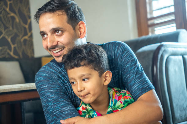 istock Young father carrying son while sitting in living room during weekend 2165983478
