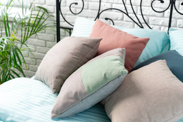 istock Soft Colorful Pillows on a Blue Bed With Black Metal Headboard 2165984808