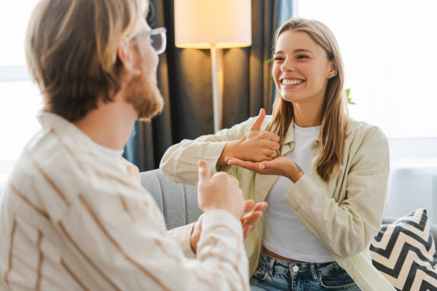 Young woman smiling and gesturing while using sign language with therapist