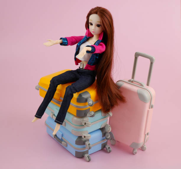 istock Common plastic doll sitting on many travel suitcases. 2165988203