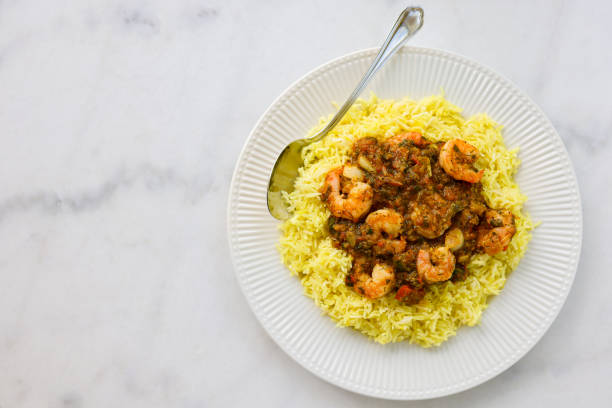 Shrimp biryani on white plate and on marble bistro table. Directly above.