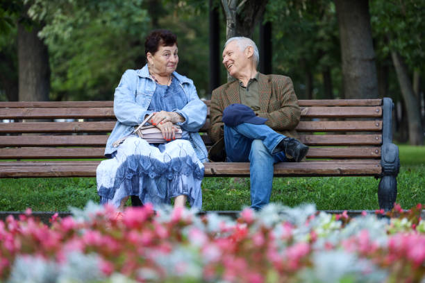 Moscow, Russia - August 7, 2024: Old man and woman talking on a bench in summer park