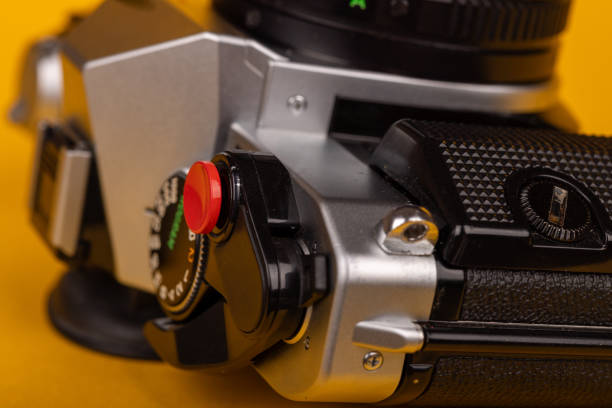istock Detail of a classic camera lying flat, showcasing its red shutter button against a vivid yellow backdrop 2166005680