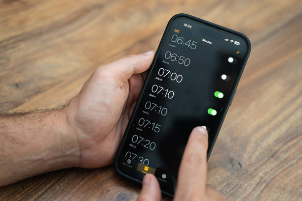 istock Person holds smartphone setting time on alarm clock app ensuring to receive notifications to wake up 2166010589