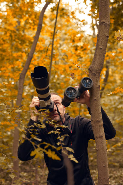 istock Man using binoculars and camera for birdwatching and other observing animals in nature. 2166016725