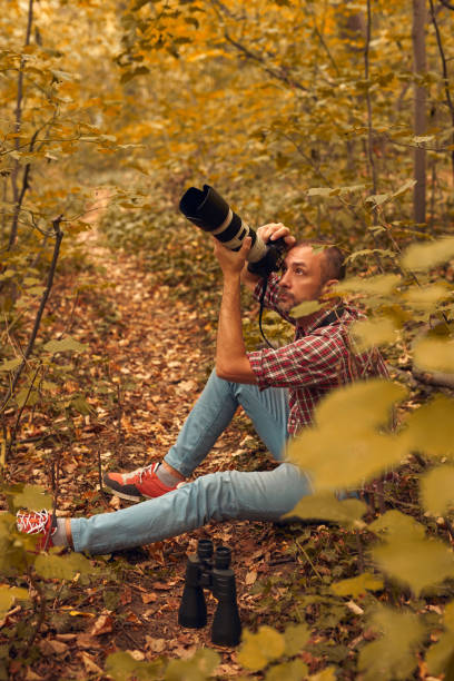 istock Man using binoculars and camera for birdwatching and other observing animals in nature. 2166016744