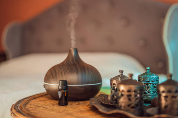 aroma oil diffuser with aroma oil on table at home. air freshener - diffuseur  huile essentielles photos et images de collection