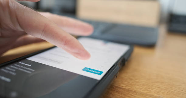 istock Man's finger presses checkout button on smartphone screen. Side view, close-up. Concept of online payment, purchase, shopping. 2166024639