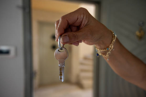Woman holding a key inside the house, selling the house
