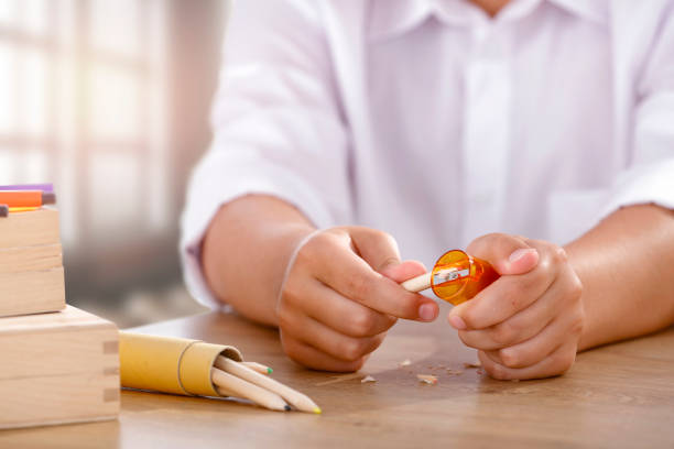 istock A student sitting at a school desk in a classroom and sharpening crayons 2166027859