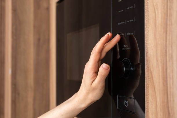 istock Woman hand pressing start button on microwave oven 2166031545
