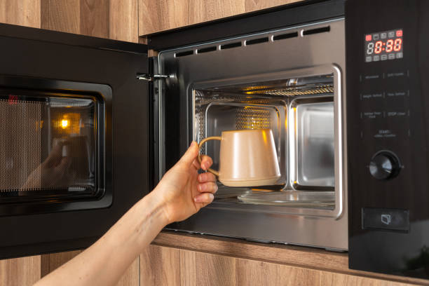 istock Person placing mug with drink in microwave 2166031548