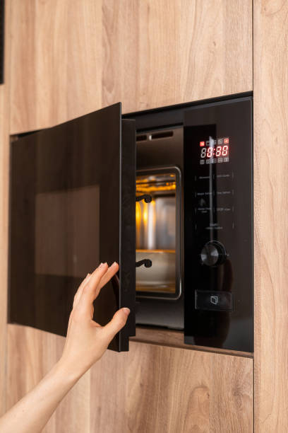 Person opening modern black microwave oven door