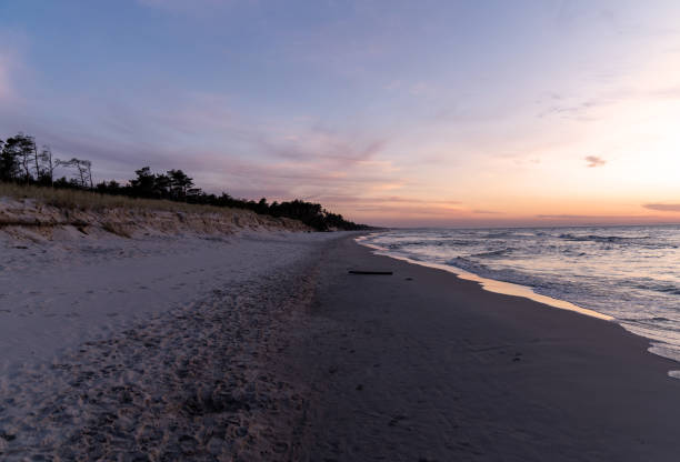 istock Setting sun illuminating the sea and the sandy beach 2166031989