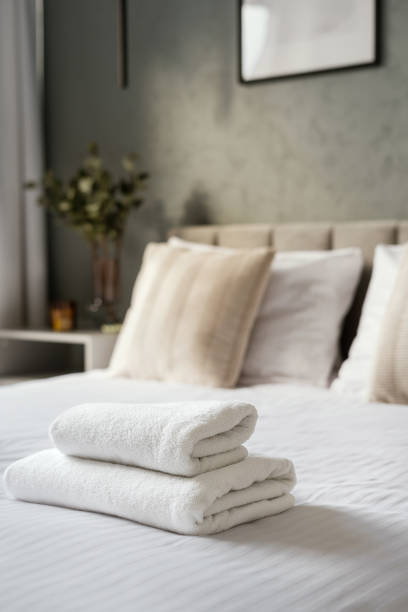istock Bed neatly made with a white blanket and two folded towels on top 2166032391