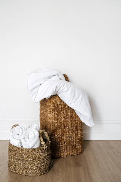 istock Wicker basket with clean folded towels, blanket, cotton bedding and down duvet 2166032395