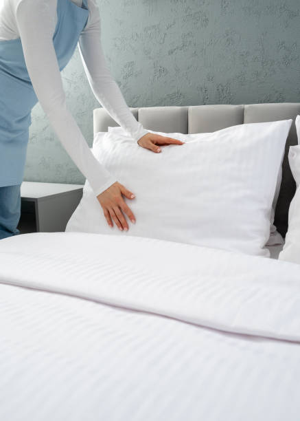 istock Maid in blue apron making bed in hotel room 2166032403