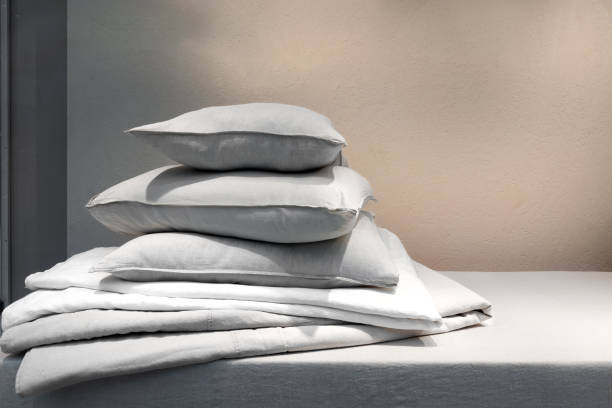 Laundry day. Clean bedding, pillows and down blanket on mattress in bedroom