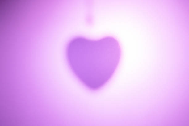 Backlit heart silhouette on pink paper background
