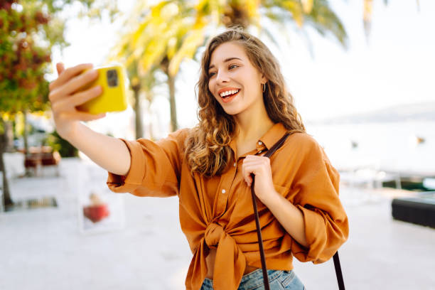 istock Young woman walks the streets and takes selfie using smartphone camera. 2166042100