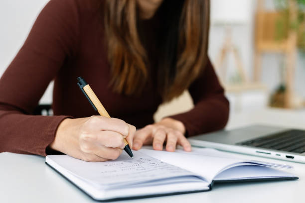 istock Close up view of female hands writing on notepad sitting at table 2166043469