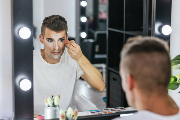 istock Man looking in the mirror while doing his makeup with a sponge in the dressing room. 2166046892
