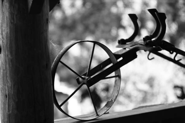 old rustic agricultural tool with a wheel and a spider's web, black and white photo