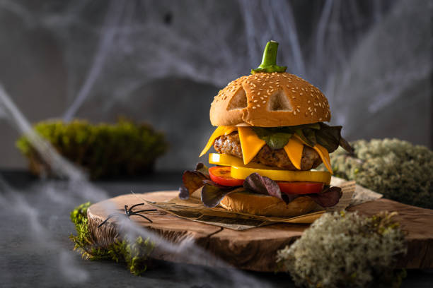 istock Funny pumpkin burger with a big cutlet. Creative Halloween cheeseburger with cheese, cutlet, tomato, pepper, salad on wooden board on dark background with moss. Copy space. Restaurant menu, recipe 2166053317
