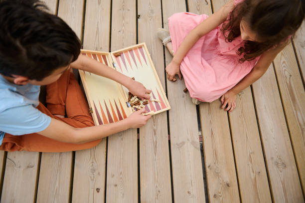 istock Children playing a board game on a wooden deck on a sunny day 2166053415
