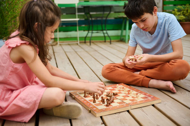 istock Two kids playing chess on a wooden deck outdoors on a sunny day 2166053446