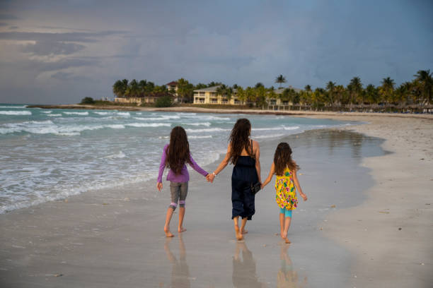 istock Family of three walk down beach, sunset 2166057673