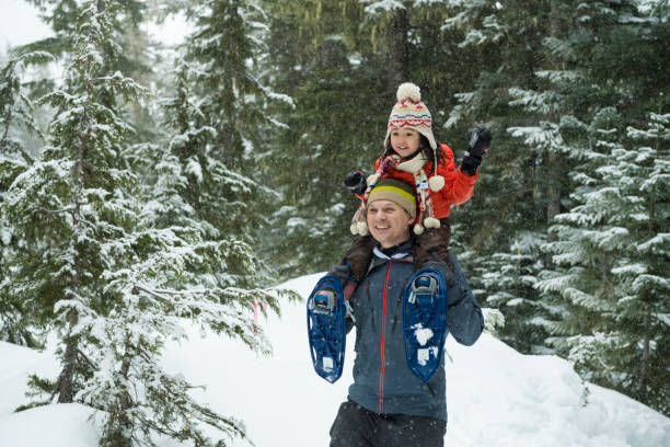 istock Father and daughter snowshoe through forest 2166059861