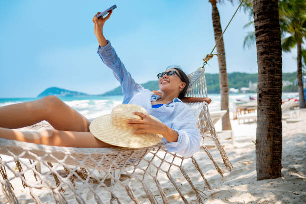 istock Woman taking a selfie on a hammock while relaxing at the beach 2166065309