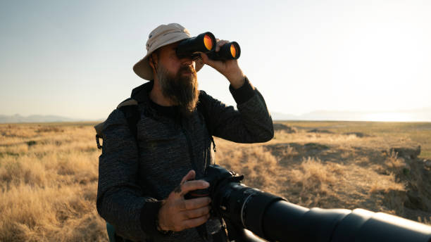 istock Adult man using binoculars and camera in nature 2166069697