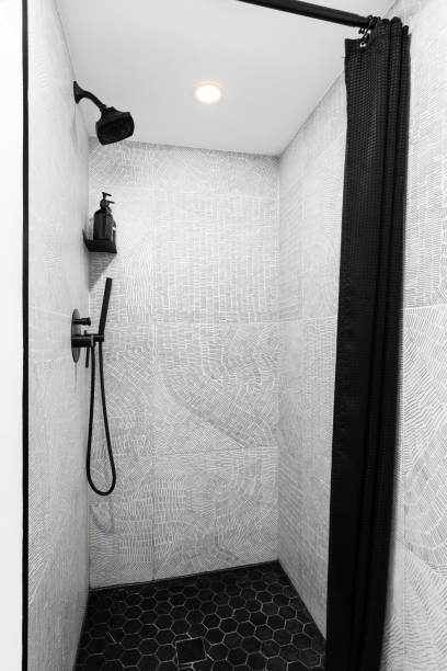 istock A shower with a black hexagon floor and brushstroke tile walls. 2166074750