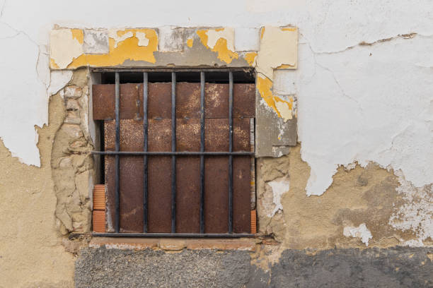 istock Rusted metal blocking a barred window in an old building. 2166079622