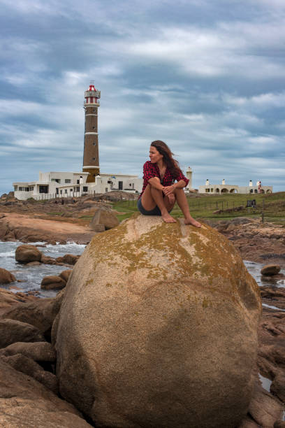 Woman sitting on a rock at the edge of the sea in Cabo Polonio on the coast of Uruguay