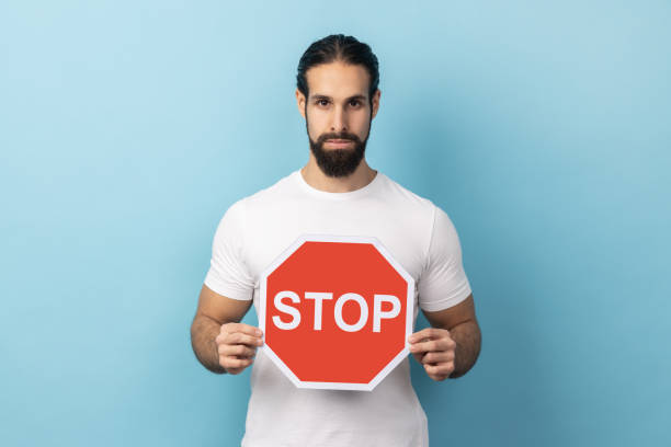 istock Man holding red Stop sign, looking at camera with negative aggressive expression, showing ban. 2166083452