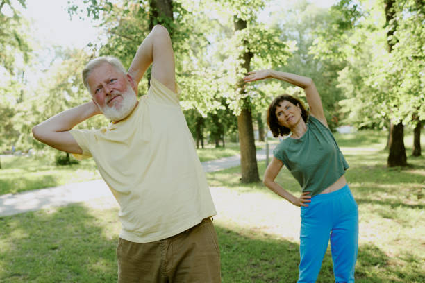 istock Gray-haired Man and Brunette Woman Doing Back Exercise 2166083601