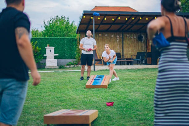 istock Two couples playing bean bag toss in the backyard 2166086084
