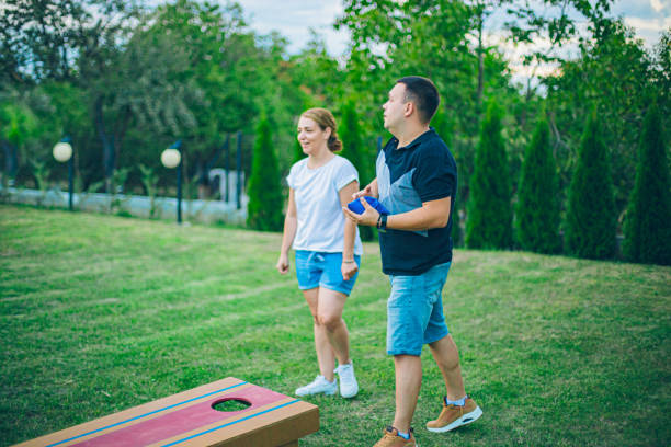 Couple playing bean bag toss in the backyard