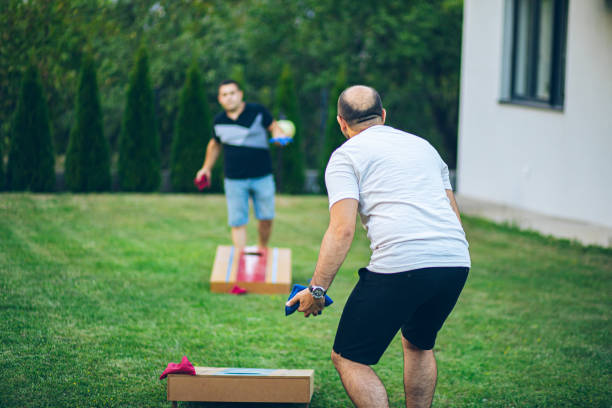 istock Two best friends playing bean bag toss in the backyard 2166086291