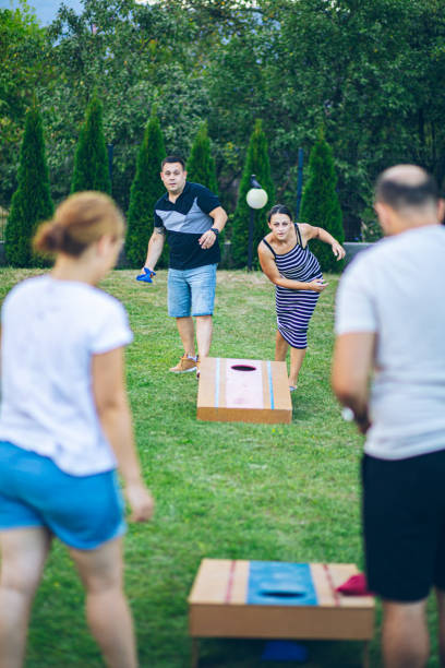 istock Two couples playing bean bag toss in the backyard 2166087100
