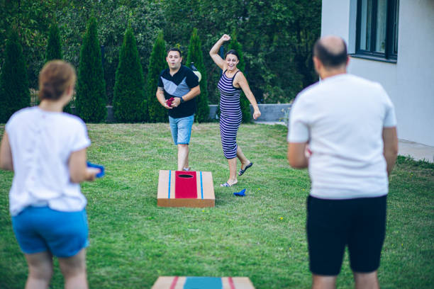 istock Two couples playing bean bag toss in the backyard 2166087157