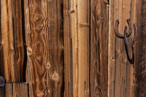 distinctive old cowboy hat is hanging on weathered wooden wall, showcasing its intricate stitching and rustic charm in rural setting. close up.