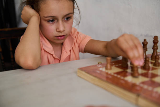 istock Young girl in deep concentration playing chess at home 2166094896