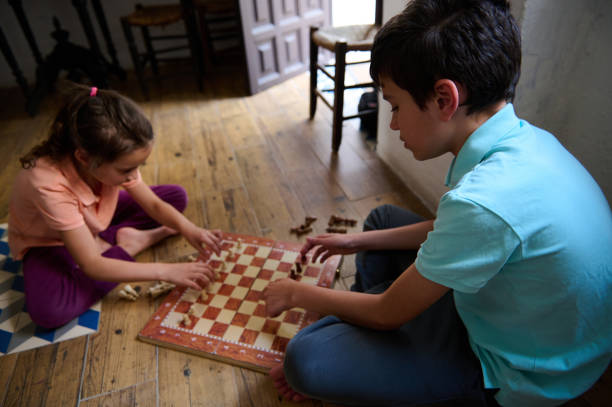 istock Two children sitting on the floor while playing a chess game at home 2166094941