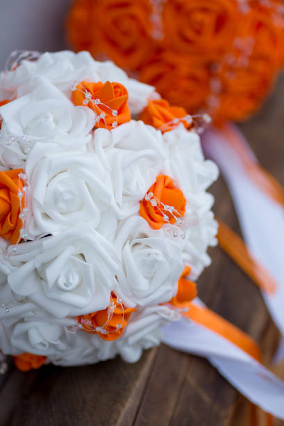 View of wedding flower bouquets with white and orange flowers for the bride and all orange flowers for the bridesmaids