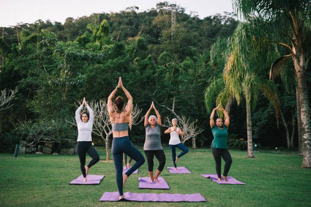 Group of women practicing Yoga outdoors with a instructor