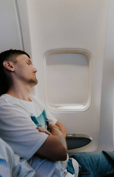 istock A young guy sleeps on an airplane near the window. 2166104703